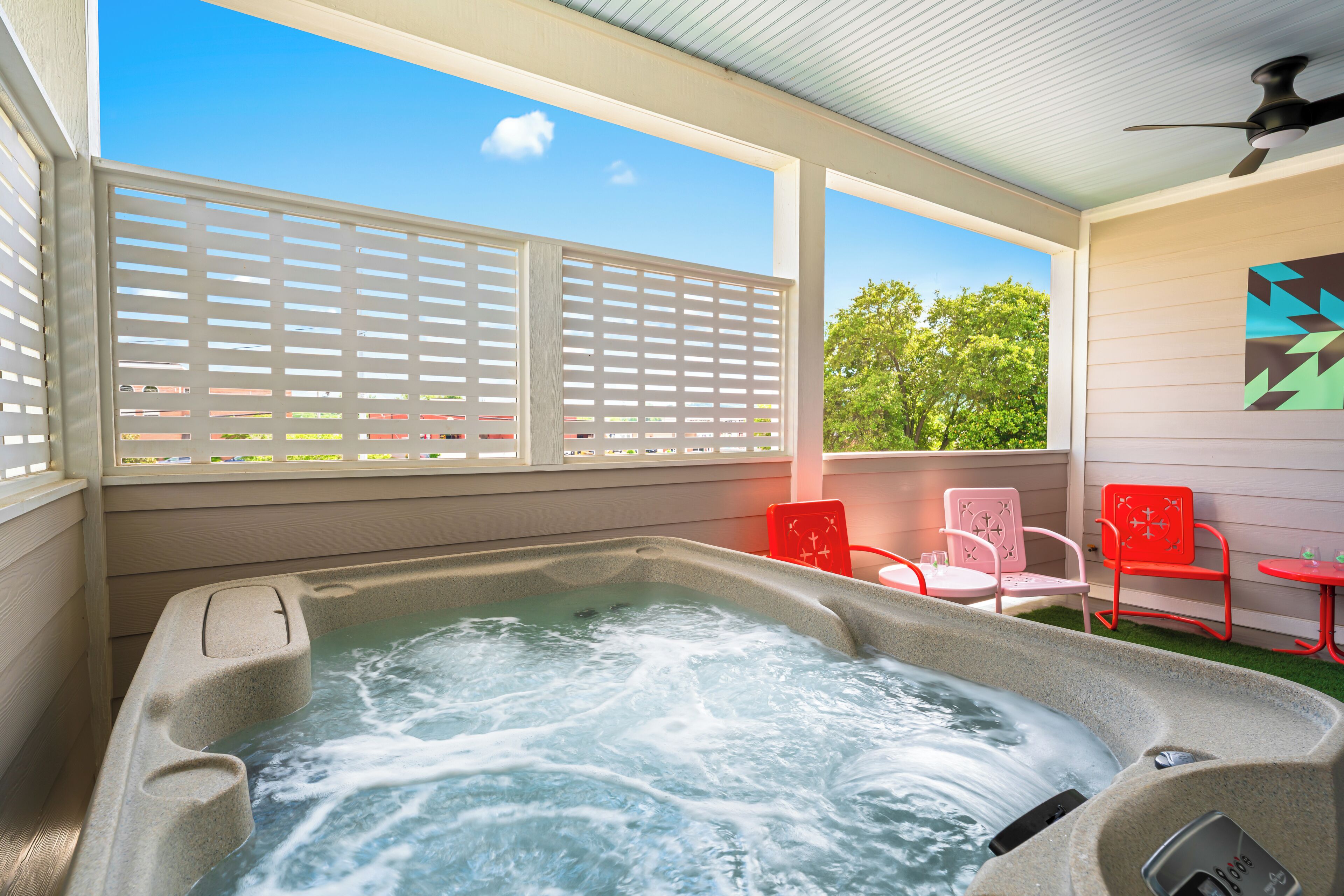 A hot tub with a view of trees and a patio area with chairs and a table.