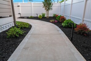A concrete pathway leading to a fenced area with various plants and shrubs. - 2BR/2BA Hot Tub Suite • Songbirds (Sevierville)