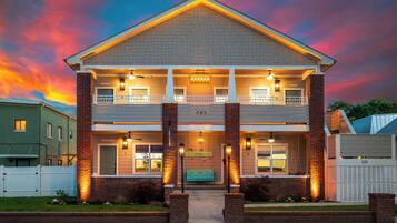 A two-story building with a balcony, a front porch, and a brick facade.
