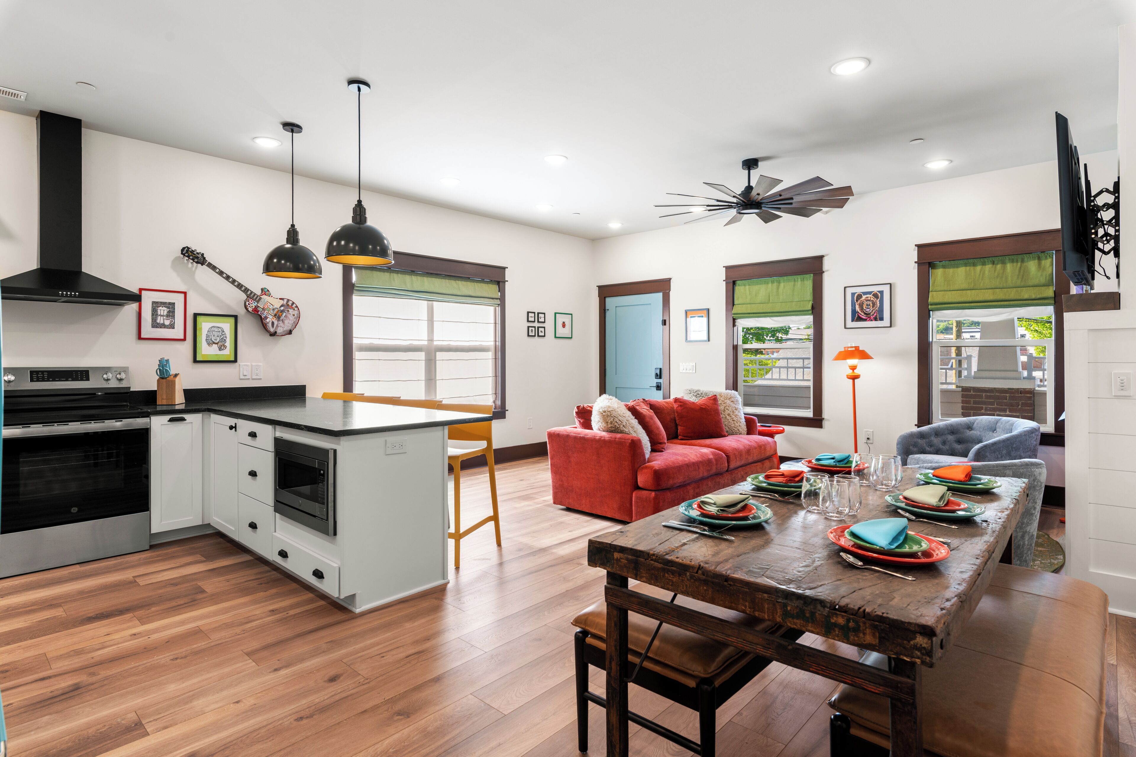 A modern kitchen with a dining area, featuring a central island, a built-in oven, and a ceiling fan.