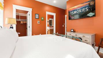 A hotel room with a large bed, a dresser, a mirror, and a wall with a framed picture.