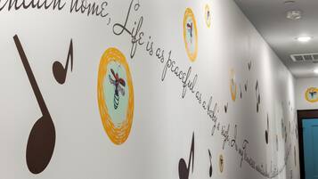 Pared con detalles decorativos, incluyendo notas musicales, una mariposa y texto.