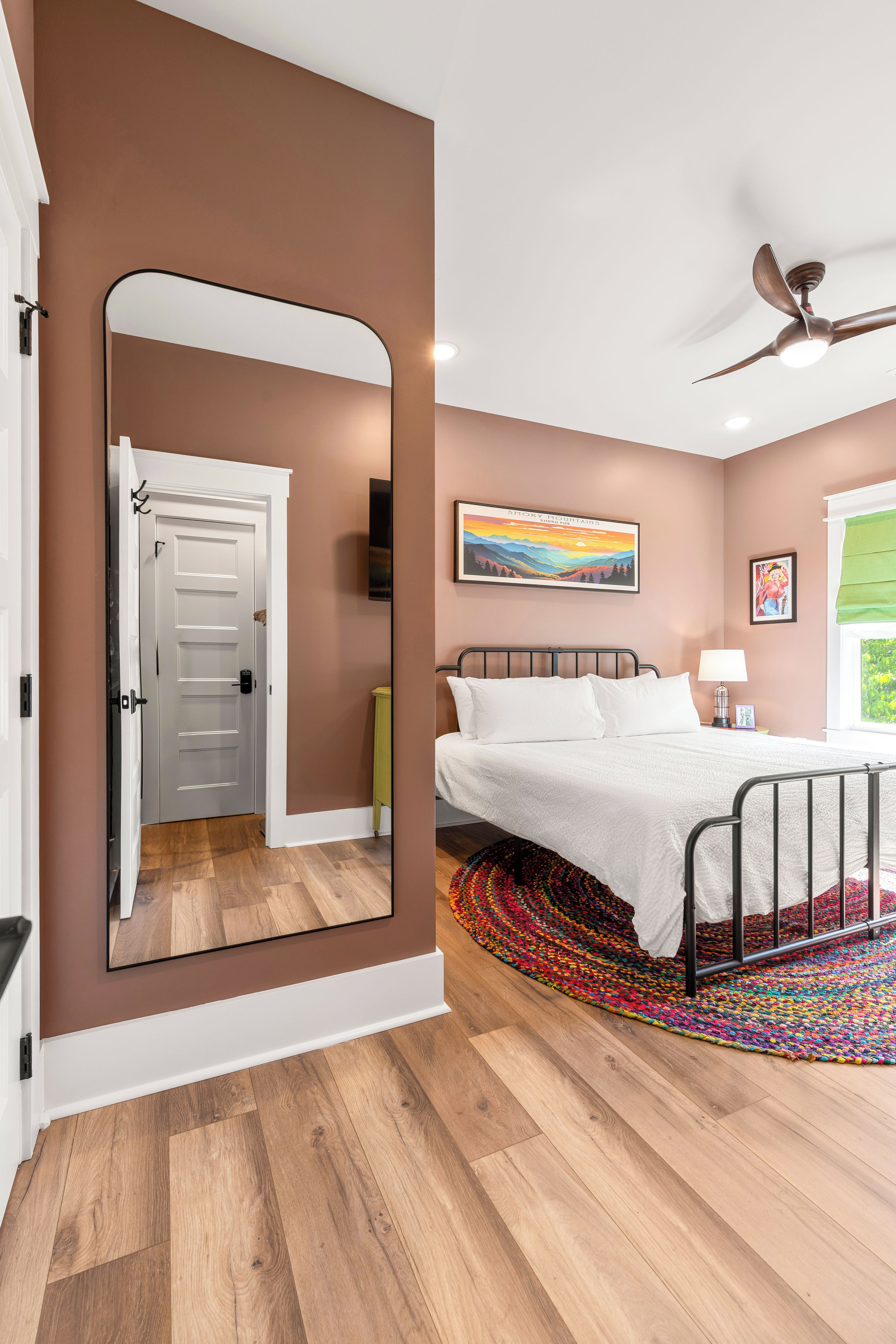 Una camera da letto con un letto, una ventola a soffitto, un quadro e una porta.