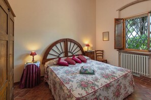 A bedroom with a bed, a nightstand, a chair, a window, and a radiator. - Oliveta Gufo With 1 Bedrooms and 1 Bathrooms (Poggibonsi)