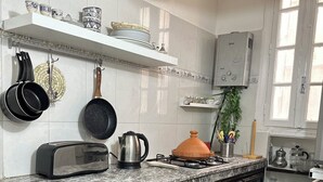 A kitchen with a marble countertop, hanging pots, a coffee maker, and a refrigerator. - Spacious 2-Bedroom Apartment in Central Casablanca – Sleeps 5 (Casablanca)
