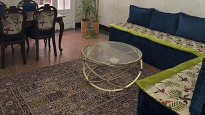 A living room with a round glass coffee table, a sofa, a dining table with chairs, and a chandelier. - Spacious 2-Bedroom Apartment in Central Casablanca – Sleeps 5 (Casablanca)