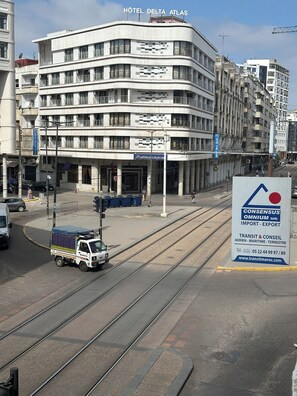 Ein mehrstöckiges Gebäude mit einem Schild für 'HOTEL DELTA ATLAS' und einer Straßenbahn, die davor verläuft.