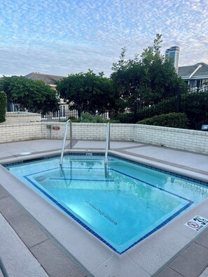Ein rechteckiger Pool mit blau gefliestem Rand, umgeben von einer niedrigen Mauer, und einer Metallleiter, die ins Wasser führt.