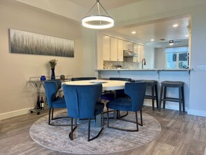 A dining area with a round table and blue chairs, a kitchen with white cabinets, and a ceiling fan. - Welcome to your dream retreat in Lantern Bay Villas (Dana Point)