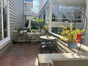 A small outdoor patio with a round table and chairs, surrounded by potted plants and a railing. - Welcome to your dream retreat in Lantern Bay Villas (Dana Point)