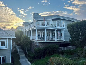 A two-story house with a balcony, a flag, and a staircase leading to the entrance. - Welcome to your dream retreat in Lantern Bay Villas (Dana Point)