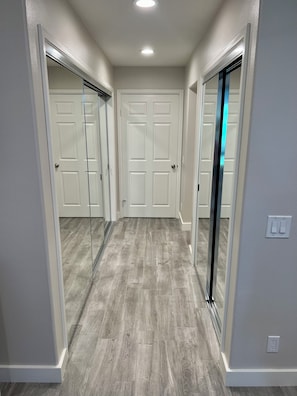 A hallway with a light gray floor, white walls, and a white door at the end.