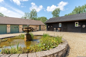 A courtyard with a fountain, stone buildings, and a bicycle. - 1641 Historic Farmhouse Sleeps 16 Bath Bristol (Bristol)