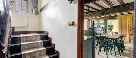 A staircase with wooden steps leading to a kitchen area with a dining table and chairs.