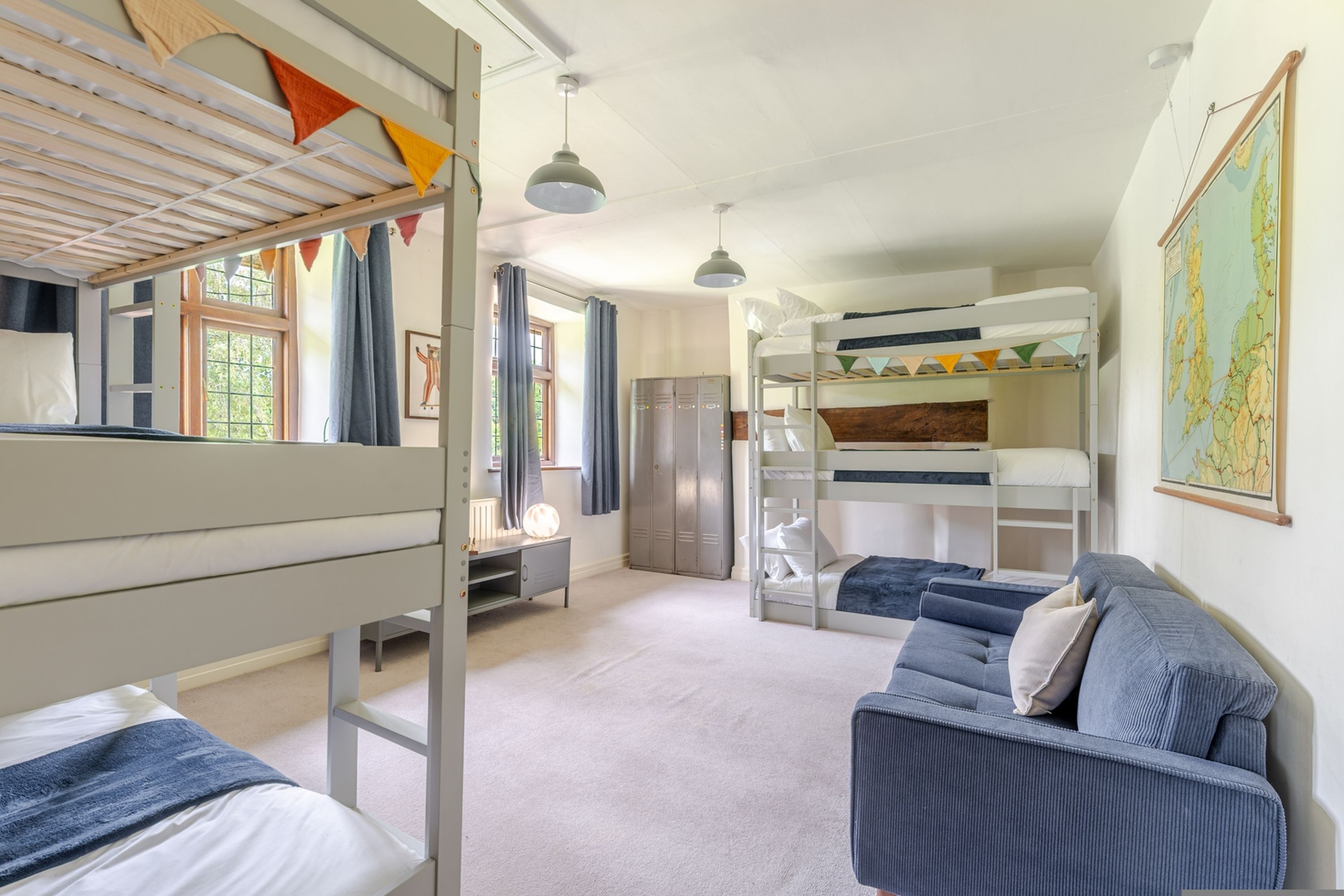 A bunk bed room with a desk, a sofa, and a map on the wall.