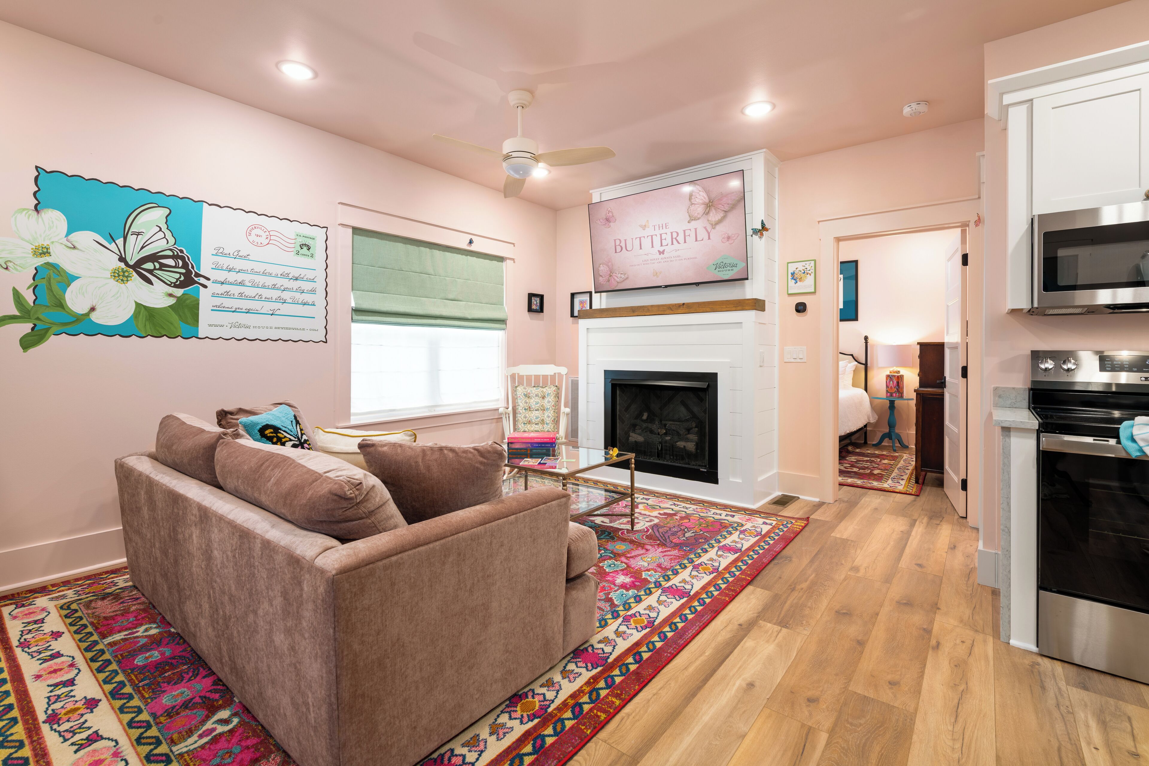 A cozy living room with a fireplace, a sofa, and a colorful rug.