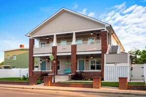 A two-story building with a balcony, a front porch, and a garage door. - 1BR Hot Tub Suite • Butterfly (Sevierville)