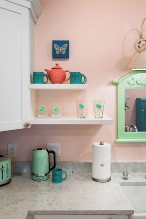 A kitchen with a white countertop, a teal kettle, a red teapot, and a teal mug. - 1BR Hot Tub Suite • Butterfly (Sevierville)