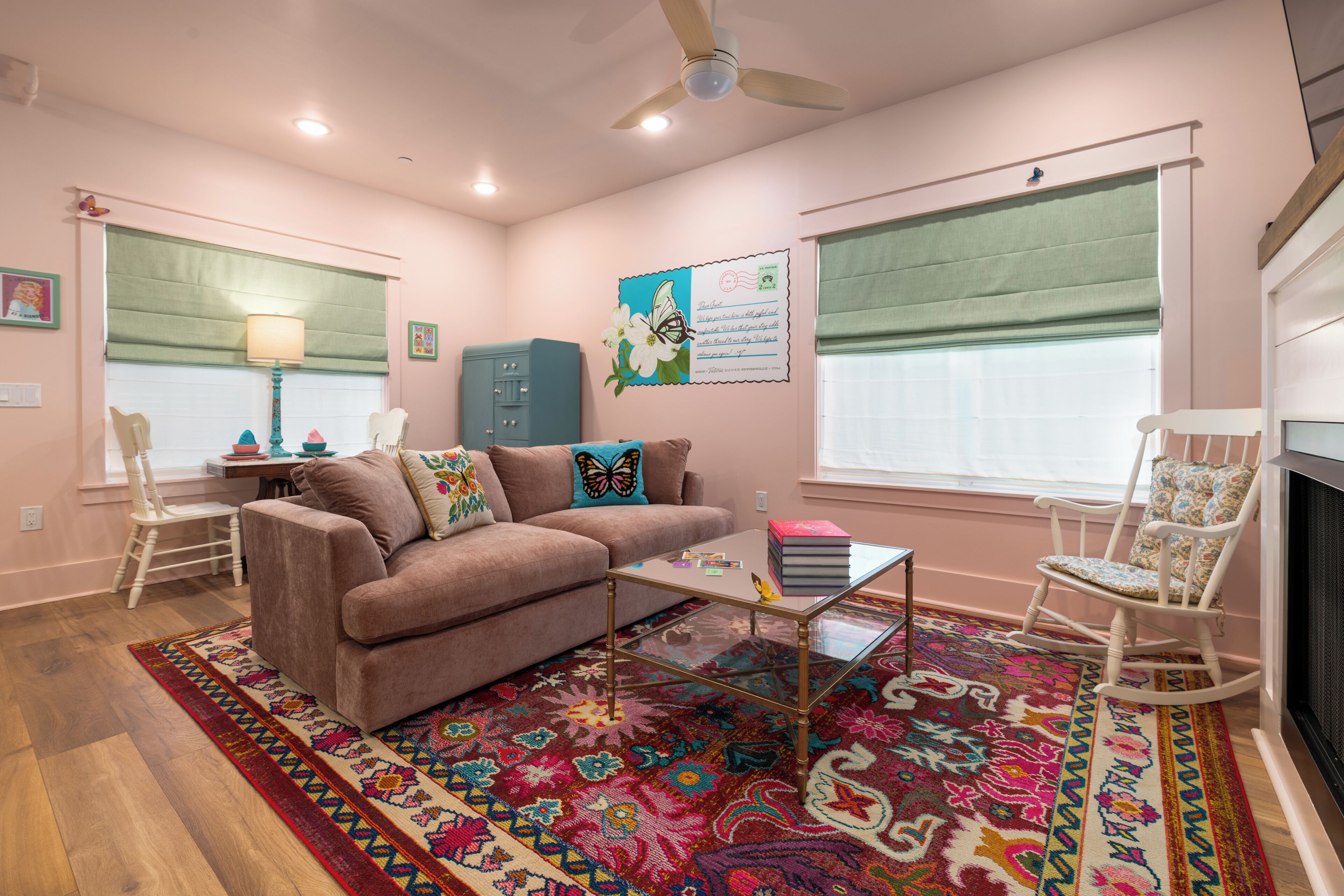 A living room with a sofa, a coffee table, a patterned rug, a rocking chair, and a window with a view.