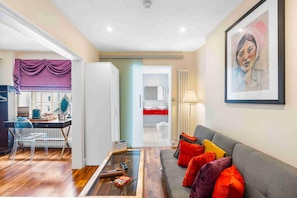 A modern living room with a sofa, a coffee table, and a dining area with a chair and table. - Orien tal By My Getaways (Brighton)