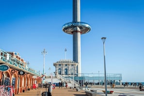 A coastal promenade with a tall tower, a covered walkway, and a building with arched windows. - Orien tal By My Getaways (Brighton)