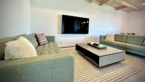 Una sala de estar moderna con dos sofás, una mesa de centro y un televisor de pantalla plana montado en la pared.