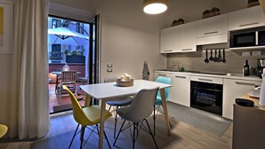 Una cucina moderna con mobili bianchi, un forno a microonde e un lavello. C'è un'area pranzo con tavolo e sedie bianche.