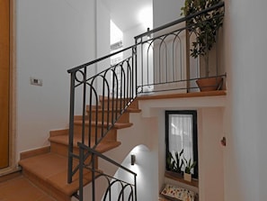 A staircase with a metal railing, wooden steps, and a small window with plants. - Le Terrazze sul Cortile - Red (Salerno)