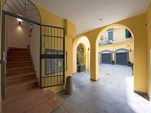 A building entrance with a staircase, a metal gate, and a paved courtyard. - Le Terrazze sul Cortile - Red (Salerno)