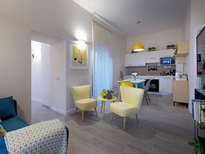 Un salon moderne comprenant un canapé, deux fauteuils jaunes, une table basse et un coin repas avec une table et des chaises.