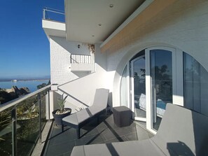 A balcony with a view of the sea, a seating area with a bench and a small table, and a glass door leading to an indoor space. - Joan Margarit 24 With 4 Bedrooms and 3 Bathrooms (Roses)