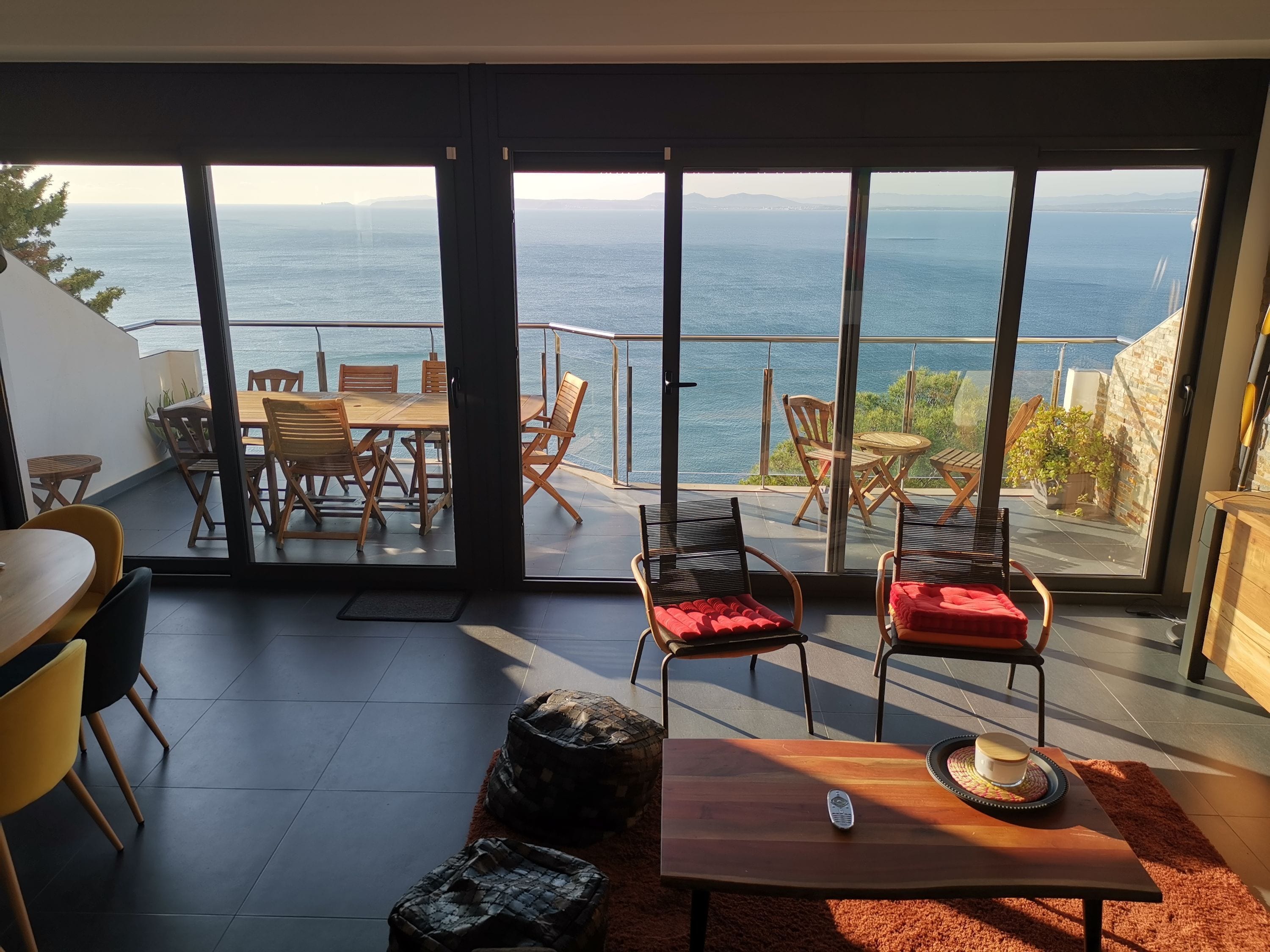 Un interior moderno con un gran ventanal corredero que da a un balcón con vistas al mar.