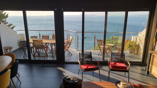 Ein modernes Interieur mit einer großen Glasschiebetür, die auf einen Balkon mit Meerblick führt.