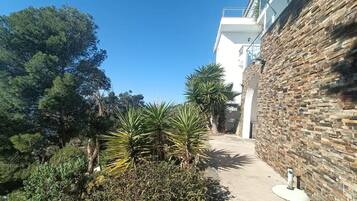 A pathway leading to a building with a stone facade and a clear blue sky.