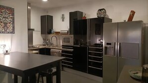 Eine moderne Küche mit Edelstahlgeräten, ein Essbereich mit Tisch und Stühlen sowie ein dekoratives Wandelement.