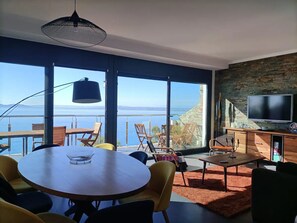 Ein modernes Wohnzimmer mit einem großen Fenster, einem runden Tisch und einem Flachbildfernseher.