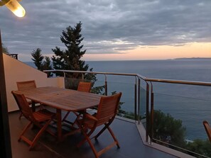 Ein Balkon mit Tisch und Stühlen, mit Blick auf ein Gewässer.