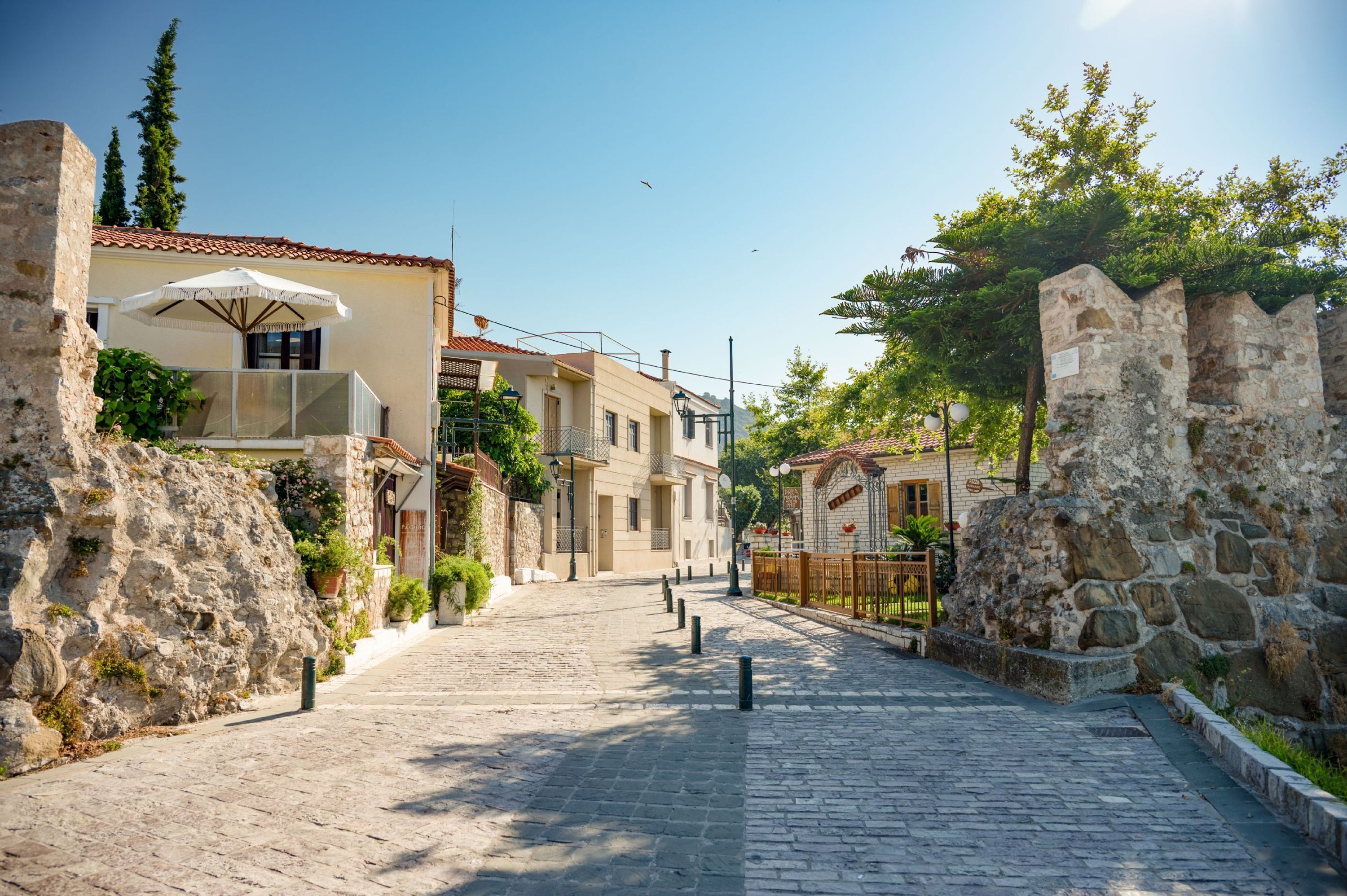 Une rue pavée bordée de murs en pierre et de bâtiments traditionnels dotés de balcons.