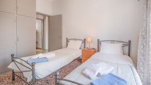 Ein Schlafzimmer mit zwei Einzelbetten, einem Nachttisch, einem Kleiderschrank und einer Tür zu einem anderen Raum.