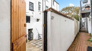 A narrow alleyway with a white building, a wooden gate, and a number '33' on a wall. - Simply Boho By My Getaways (Brighton)