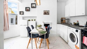 A compact kitchen with a dining area, a washing machine, and a fireplace. - Simply Boho By My Getaways (Brighton)