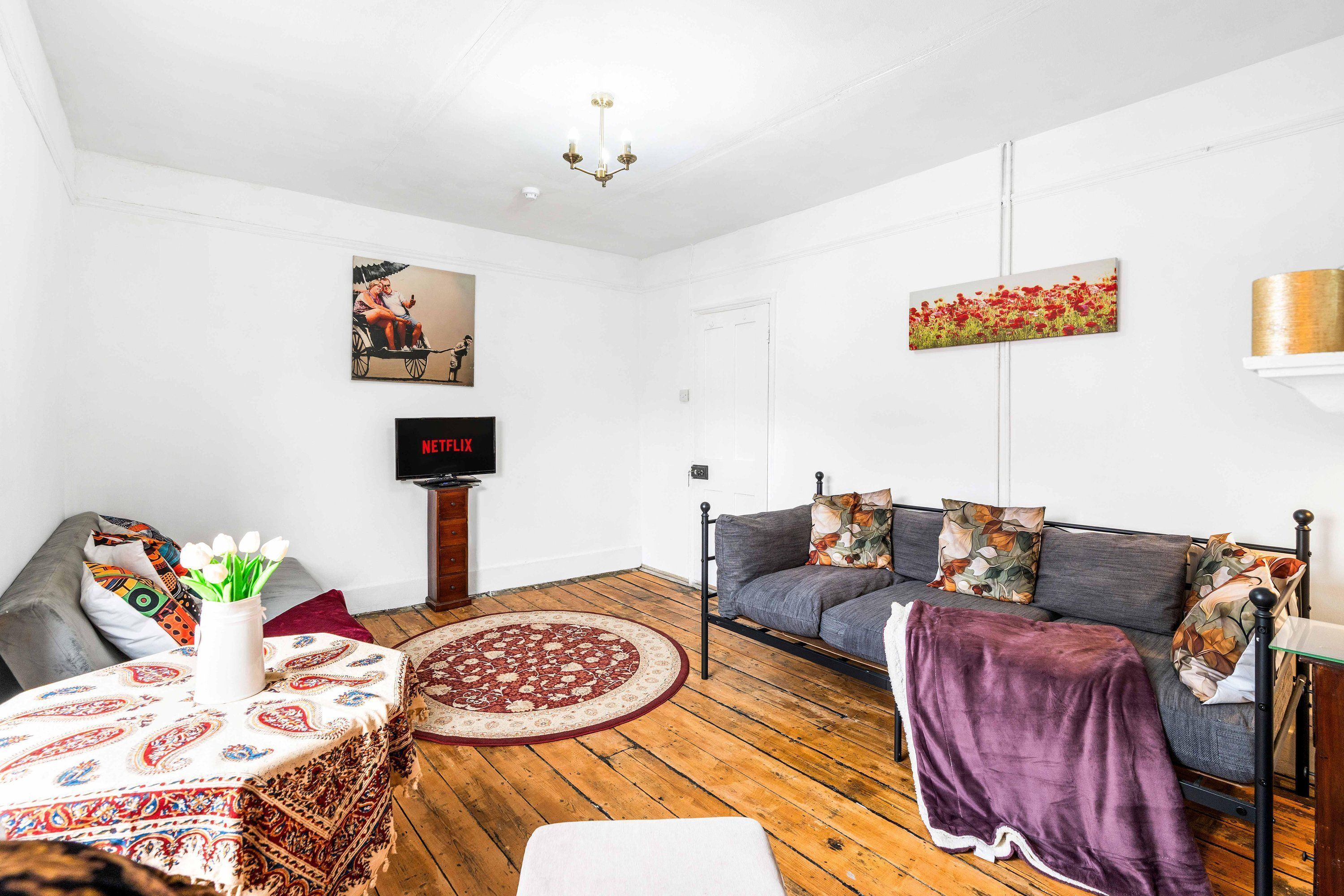 A living room with a sofa, a TV, a chandelier, and artwork on the walls.