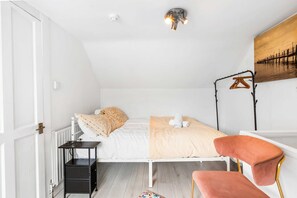 Ein Schlafzimmer mit Bett, Nachttisch, Stuhl, Heizkörper und einer Wandleuchte.