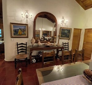 A dining area with a large mirror, wooden chairs, a glass-top table, and a chandelier. - Cozy 4-Bedroom Villa in Casa de Campo (La Romana)