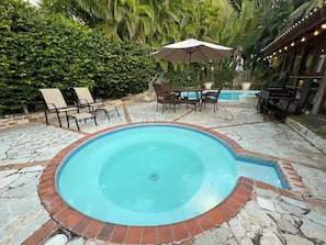 A swimming pool with a brick border, surrounded by lounge chairs and a table with an umbrella. - Cozy 4-Bedroom Villa in Casa de Campo (La Romana)