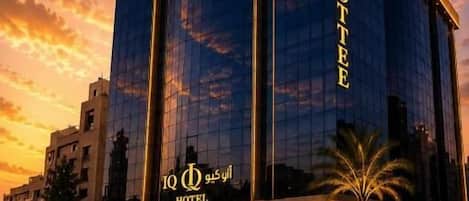 A modern hotel with a prominent glass facade and a sign indicating it is the 'IQ Hotel.'