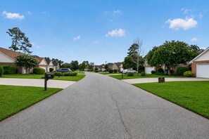 A residential street with houses on both sides, a clear sky, and a mailbox on the left. - Modern Tifton Getaway - 3BR + Pool Access (Tifton)