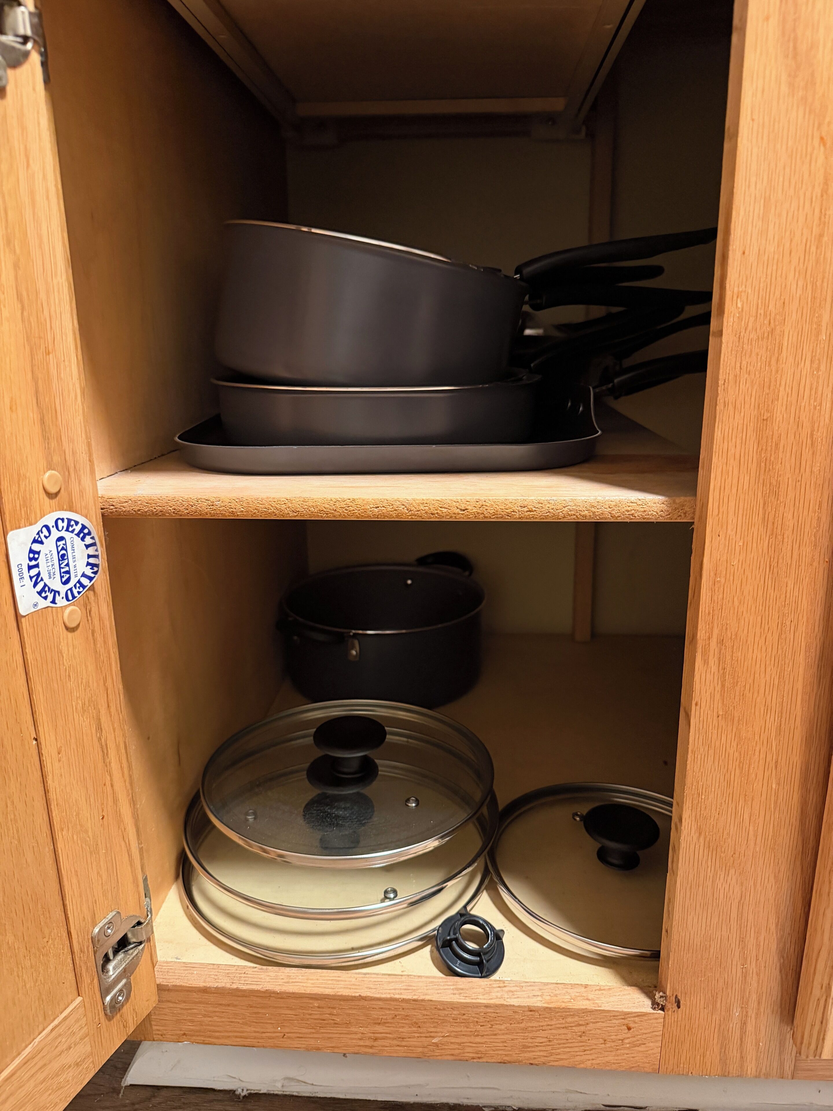 A kitchen cabinet with shelves holding cookware.