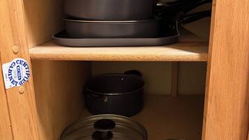 A kitchen cabinet with shelves holding cookware.