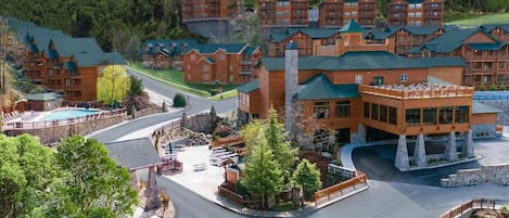 Un refugi amb diversos edificis de fusta, un pati central amb piscina i un paisatge de muntanyes al fons.